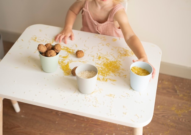 Ragazza del bambino che gioca con la pasta e il riso ai grani di noci seduti a tavola Educazione allo sviluppo precoce sensoriale per il bambino Giochi utili per bambini Concetto di abilità motorie fine Messa a fuoco selettiva