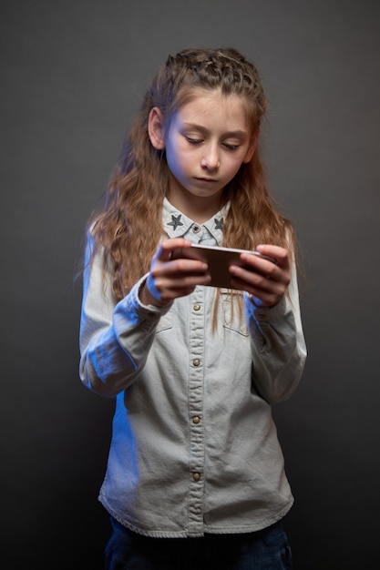 Ragazza del bambino che gioca con un telefono