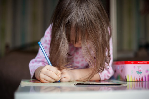 Ragazza del bambino che tiene la penna che fa i compiti a casa Concetto di studio e istruzione