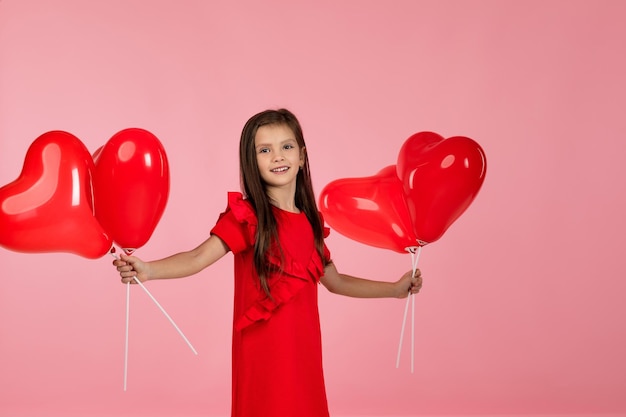 Ragazza del bambino che tiene palloncino a forma di cuore rosso