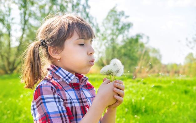 Ragazza del bambino con i denti di leone nel parco. Messa a fuoco selettiva.