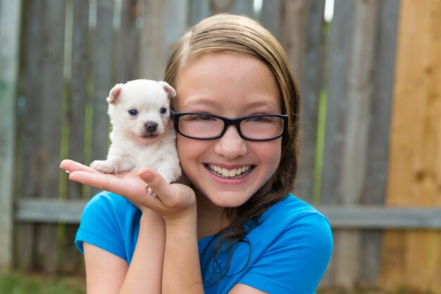 ragazza del bambino con la chihuahua dell&#39;animale domestico del cucciolo che gioca felice