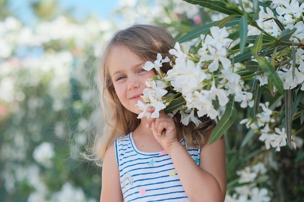 Ragazza del bambino con la natura di estate dei fiori bianchi