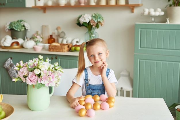 Ragazza del bambino con le uova di Pasqua in cucina. Buona Pasqua. Famiglia felice che prepara per la Pasqua.