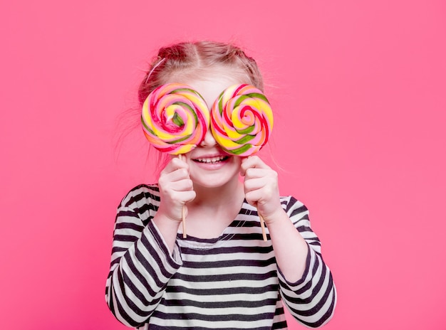 Ragazza del bambino con lecca-lecca davanti agli occhi