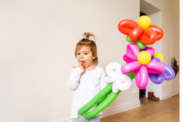 Ragazza del bambino con palloncini a forma di fiori