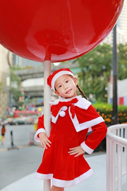 Ragazza del bambino in cappello della Santa divertirsi a Natale. Sfondo di Natale allegro.