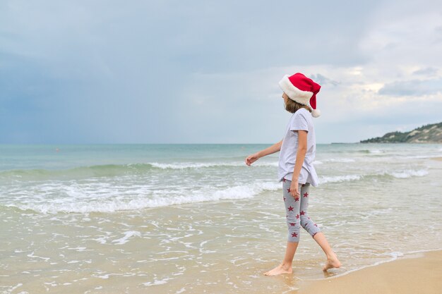 ragazza del bambino in cappello della Santa divertirsi su una spiaggia dell'oceano