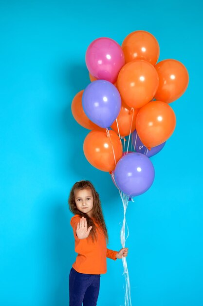 Ragazza del bambino in maglietta rosa in posa con palloncini d'aria colorati luminosi