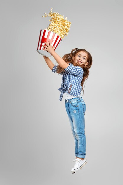 Ragazza del bambino in vetri 3d redblue che tengono secchio con popcorn volante