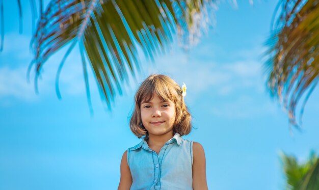 Ragazza del bambino sullo sfondo di palme e oceano. Messa a fuoco selettiva.