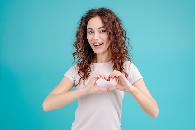 Ragazza del Brunette che mostra cuore con le sue mani isolate