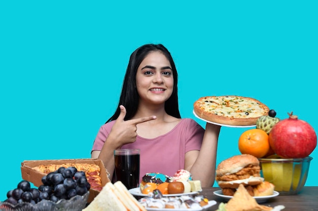 ragazza del cibo seduta al tavolo della frutta sorridente e con in mano la pizza modello pakistano indiano