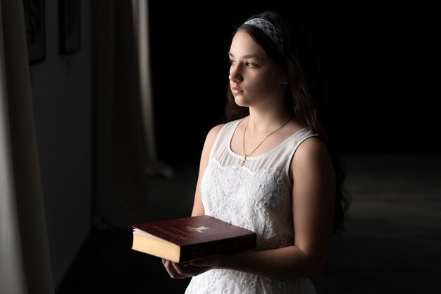 Ragazza del colpo medio che tiene la Sacra Bibbia