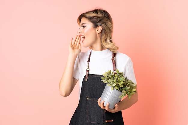 ragazza del giardiniere che tiene una pianta che grida con la bocca spalancata