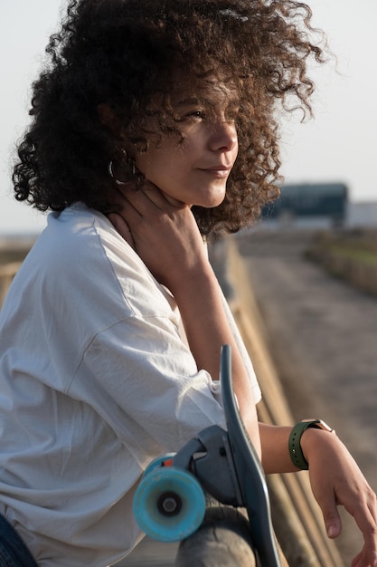 Ragazza del pattinatore con il ritratto dei capelli afro che si appoggia su un recinto