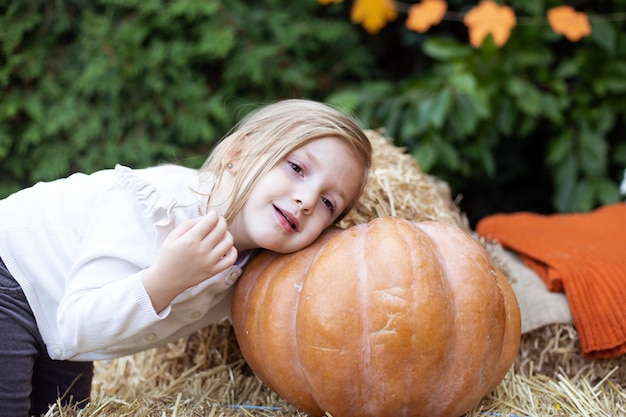 Ragazza del piccolo bambino che gioca con la zucca in giardino