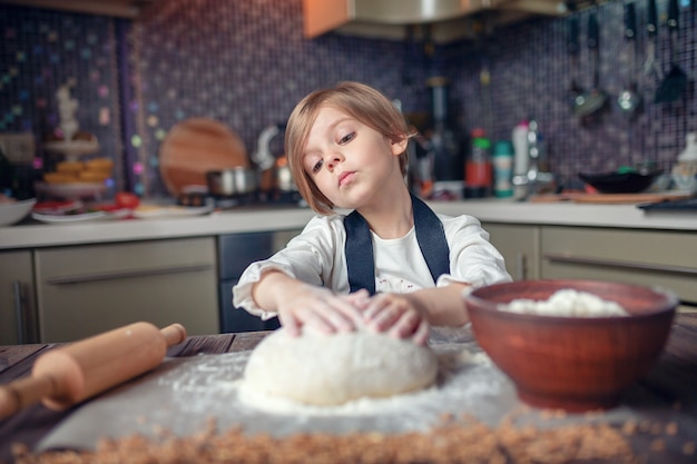 Ragazza del piccolo bambino con taglio di capelli dei capelli corti che cucina pasta