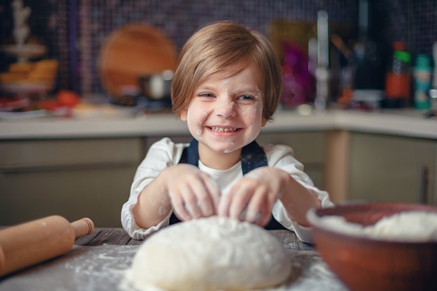 Ragazza del piccolo bambino con taglio di capelli dei capelli corti che cucina pasta