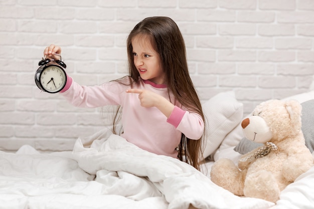 Ragazza del piccolo bambino in pigiama con l&#39;orologio