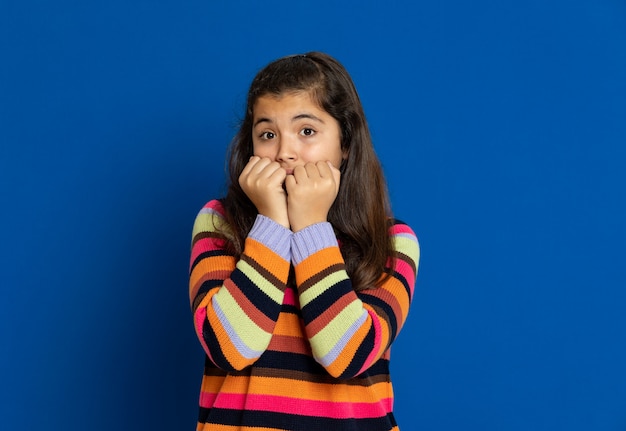 Ragazza del Preteen con la maglia a strisce che gesturing sopra la parete blu