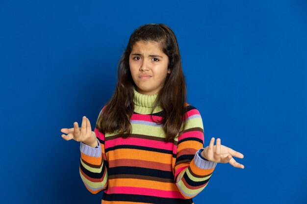 Ragazza del Preteen con la maglia a strisce che gesturing sopra la parete blu