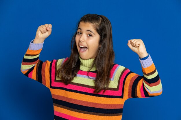 Ragazza del Preteen con la maglia a strisce che gesturing sopra la parete blu