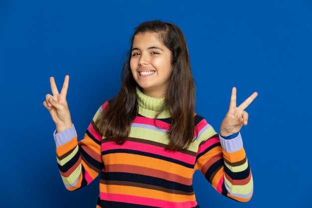 Ragazza del Preteen con la maglia a strisce che gesturing sopra la parete blu