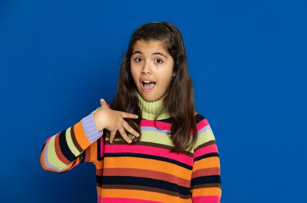 Ragazza del Preteen con la maglia a strisce che gesturing sopra la parete blu