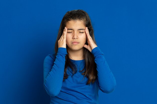 Ragazza del Preteen con la maglia blu che gesturing sopra la parete blu