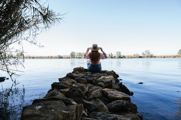 Ragazza del viaggiatore che si siede in mezzo all'acqua