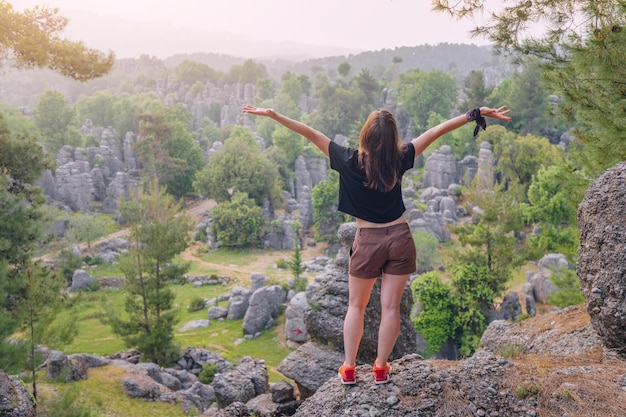 Ragazza del viaggiatore felice in piedi sulla cima della scogliera rocciosa con vista sui resti di pietra ad Altinkaya Turkiye Attrazioni e destinazioni turistiche