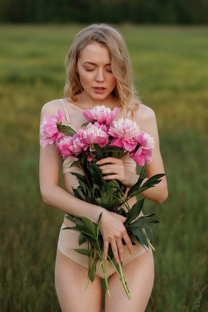 Ragazza delicata con fiori rosa nelle sue mani su uno sfondo verde