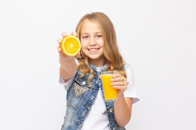 Ragazza dell'adolescente che beve il succo d'arancia che sorride mostrando le arance. Giovane bella modella caucasica. cibo salutare