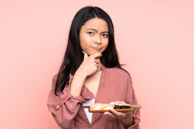Ragazza dell'adolescente che mangia i sushi isolati sulla risata rosa