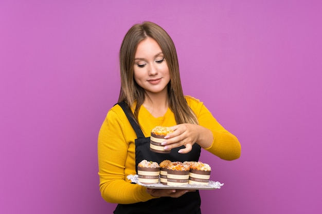 Ragazza dell'adolescente che tiene i lotti di mini torte differenti