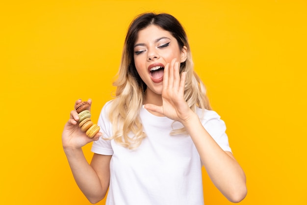 Ragazza dell'adolescente che tiene macarons francesi variopinti e gridando