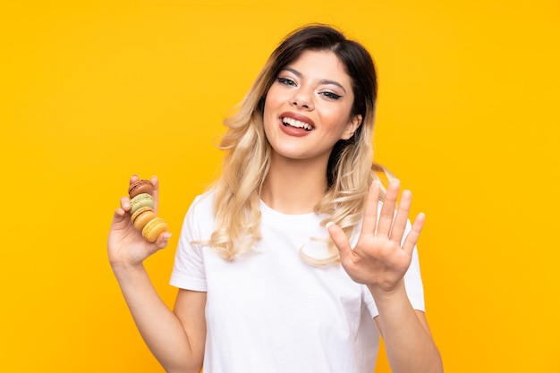 Ragazza dell'adolescente che tiene macarons francesi variopinti e saluto