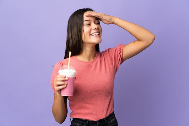 Ragazza dell'adolescente che tiene un milkshake della fragola che sorride molto