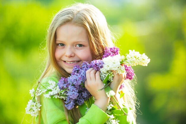 Ragazza dell'adolescente con il lillà. Ragazza di primavera in giardino fiorito. Ritratti all'aperto di bella ragazza sorridente dell'adolescente.