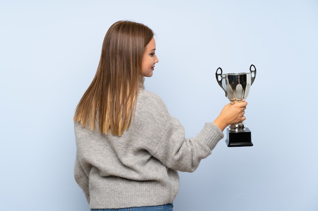 Ragazza dell'adolescente con il maglione blu che tiene un trofeo