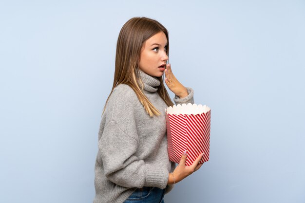 Ragazza dell'adolescente con il maglione che tiene una ciotola di popcorn