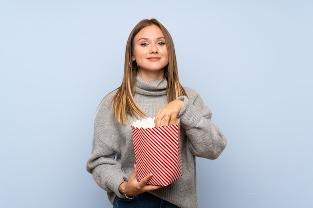 Ragazza dell'adolescente con il maglione che tiene una ciotola di popcorn