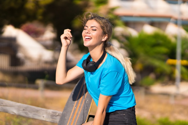 Ragazza dell'adolescente con il pattino ad all'aperto che sorride molto