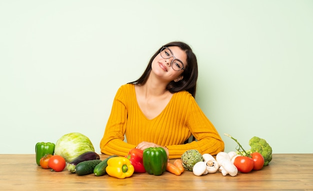 Ragazza dell&#39;adolescente con molte verdure con i vetri e sorridere