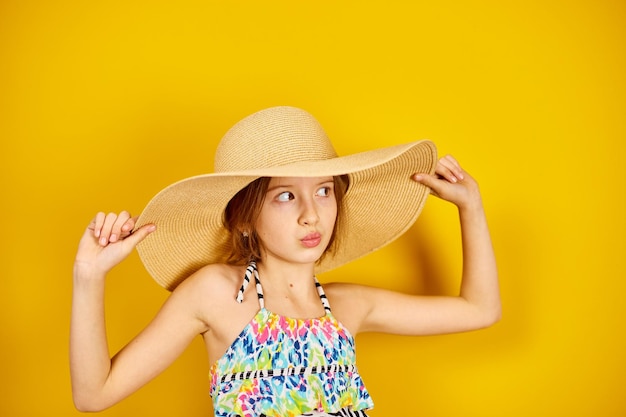 Ragazza dell'adolescente del bambino nella posa del cappello di paglia e del costume da bagno