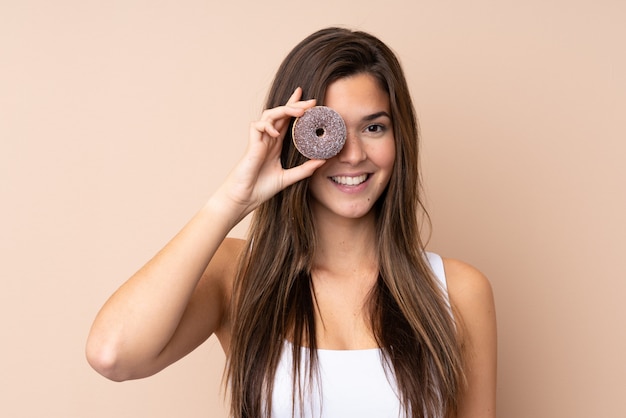 Ragazza dell'adolescente sopra la parete isolata che tiene una ciambella e felice