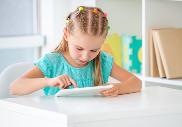 Ragazza dell'allievo che studia con l'aiuto delle nuove tecnologie