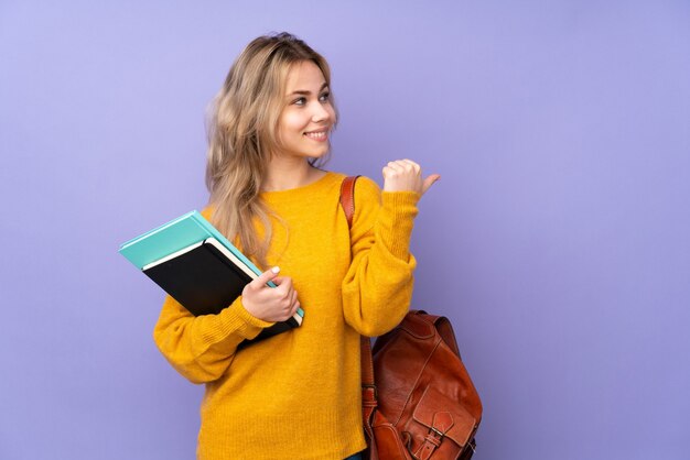 Ragazza dell'allievo dell'adolescente isolata sulla porpora che indica al lato