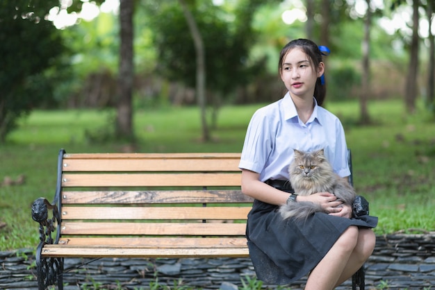 Ragazza dell&#39;Asia che porta uniforme che gioca con un piccolo gatto